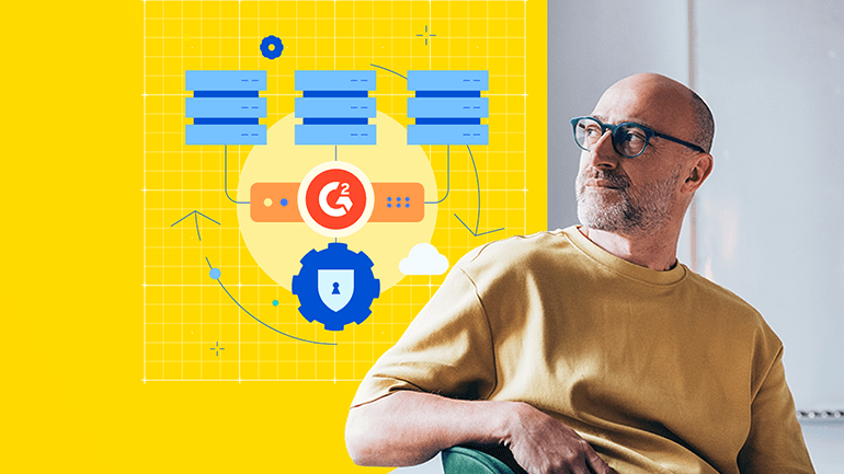 Light-skinned man wearing blue-framed glasses looking at a grid featuring a logo that consists of an orange circle and the G2 logo.